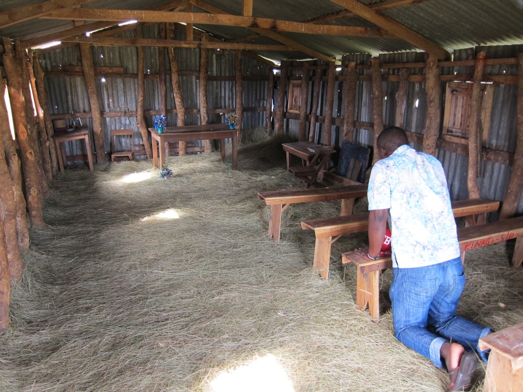 man kneeling inside small church