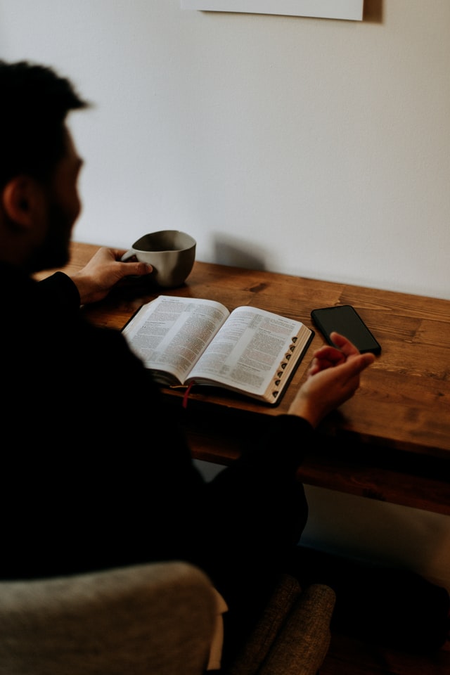 Man reading Bible with coffee and phone